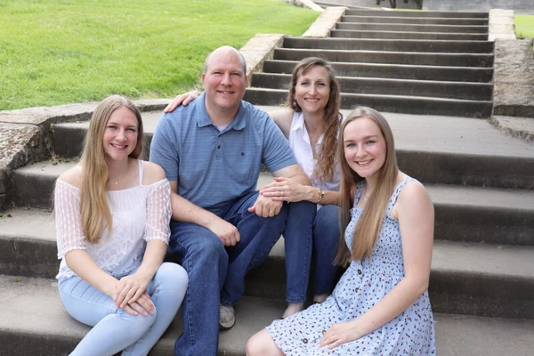 Pastor David Rolf and his family seated together outdoors.