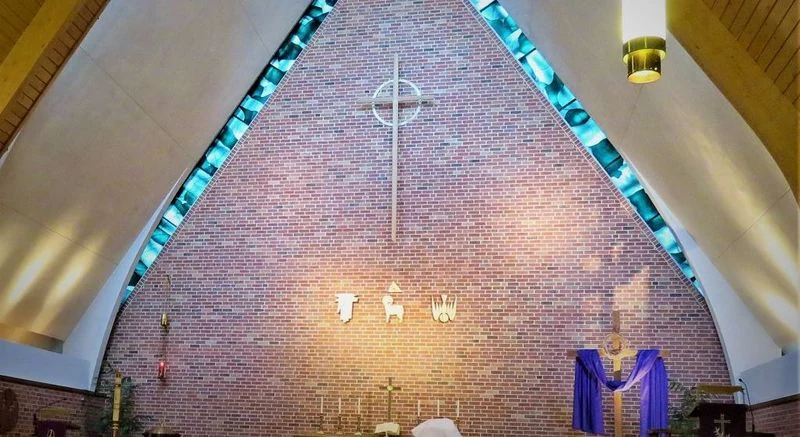 The cross and blue glass frame the brick sanctuary wall at Peace Lutheran Church.